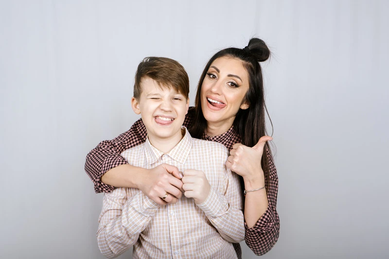 Mutter und Teenager-Sohn umarmen sich. Die Mutter macht Daumen hoch, der Sohn zwinkert. Sie rocken die Pubertät gemeinsam.